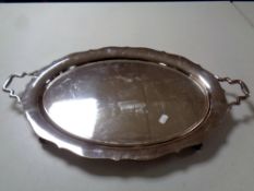 A silver plated twin handled serving tray on raised feet