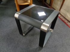 A contemporary lamp table with black glass inset panel