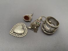 A collection of silver jewellery to include pendant on china, heart locket, ring,