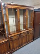 A reproduction mahogany Regency style triple door bookcase fitted cupboards and drawers beneath