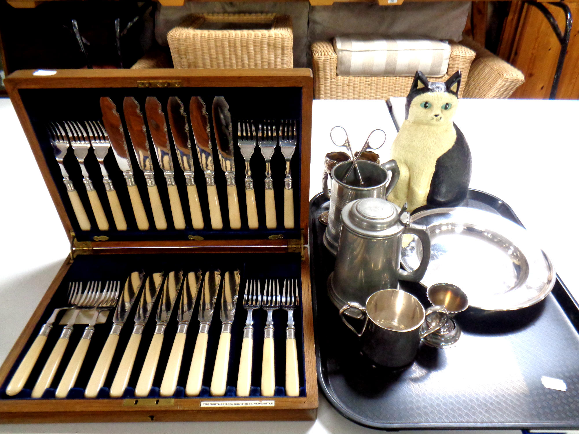 An Edwardian oak canteen of fish cutlery together with a tray containing cast iron cat doorstop and