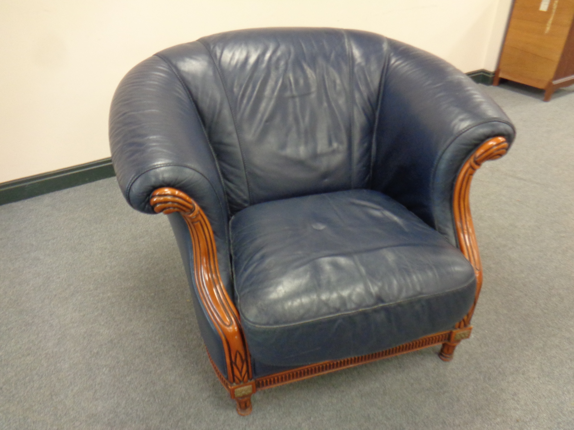 A wood framed armchair upholstered in blue leather