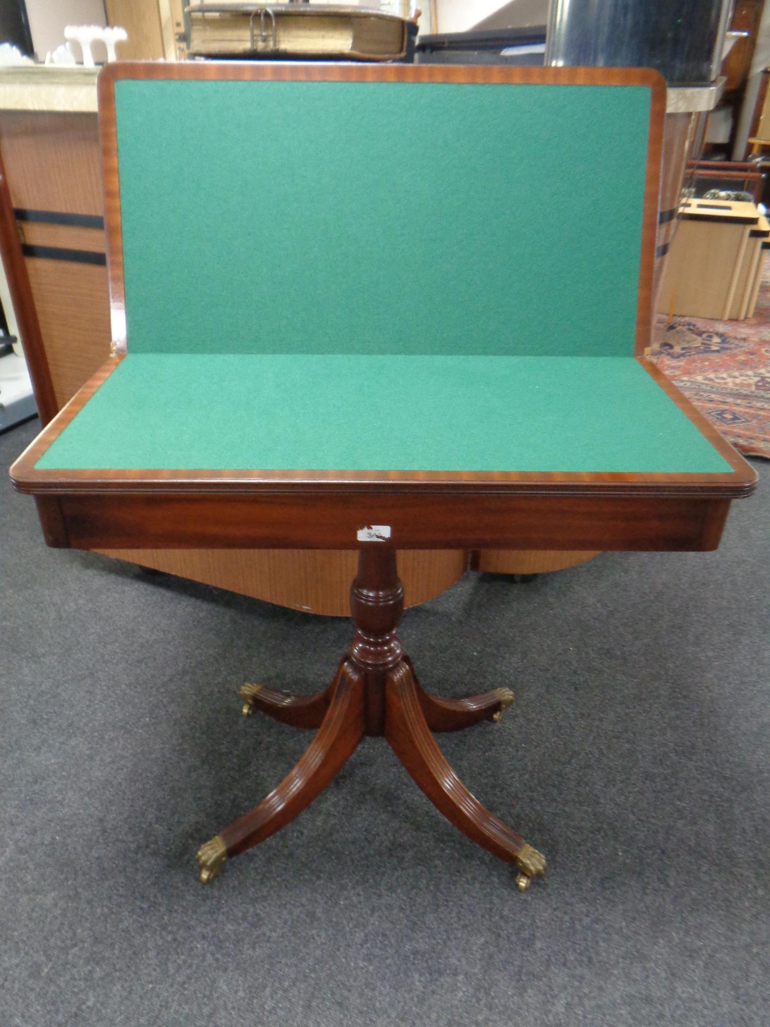 A Victorian style mahogany turnover top pedestal card table on brass capped feet