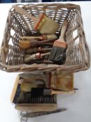 A wicker basket containing a quantity of assorted vintage paintbrushes