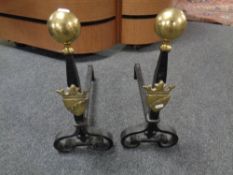 A pair of antique brass and cast iron fire dogs bearing a shield