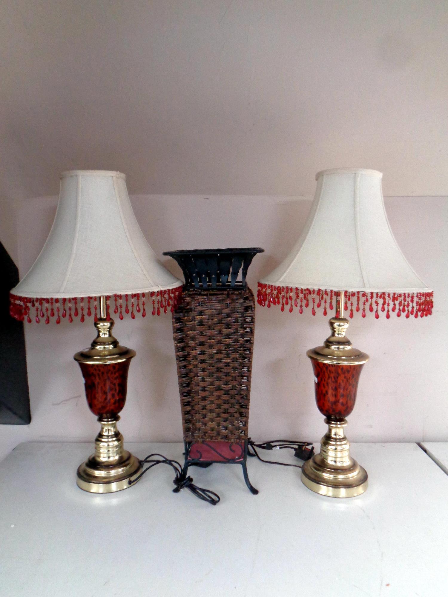 A pair of contemporary table lamps with tasseled shades together with a metal and wicker stick