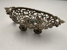 An ornate brass basket on wheels with inset green stone