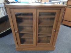 A contemporary double door sliding bookcase in a walnut finish