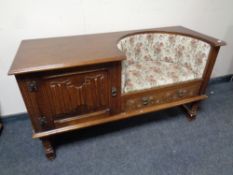 A carved oak telephone seat fitted cupboard and drawer upholstered in a tapestry fabric