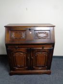 A writing bureau fitted drawer and double door cupboard beneath in an oak finish