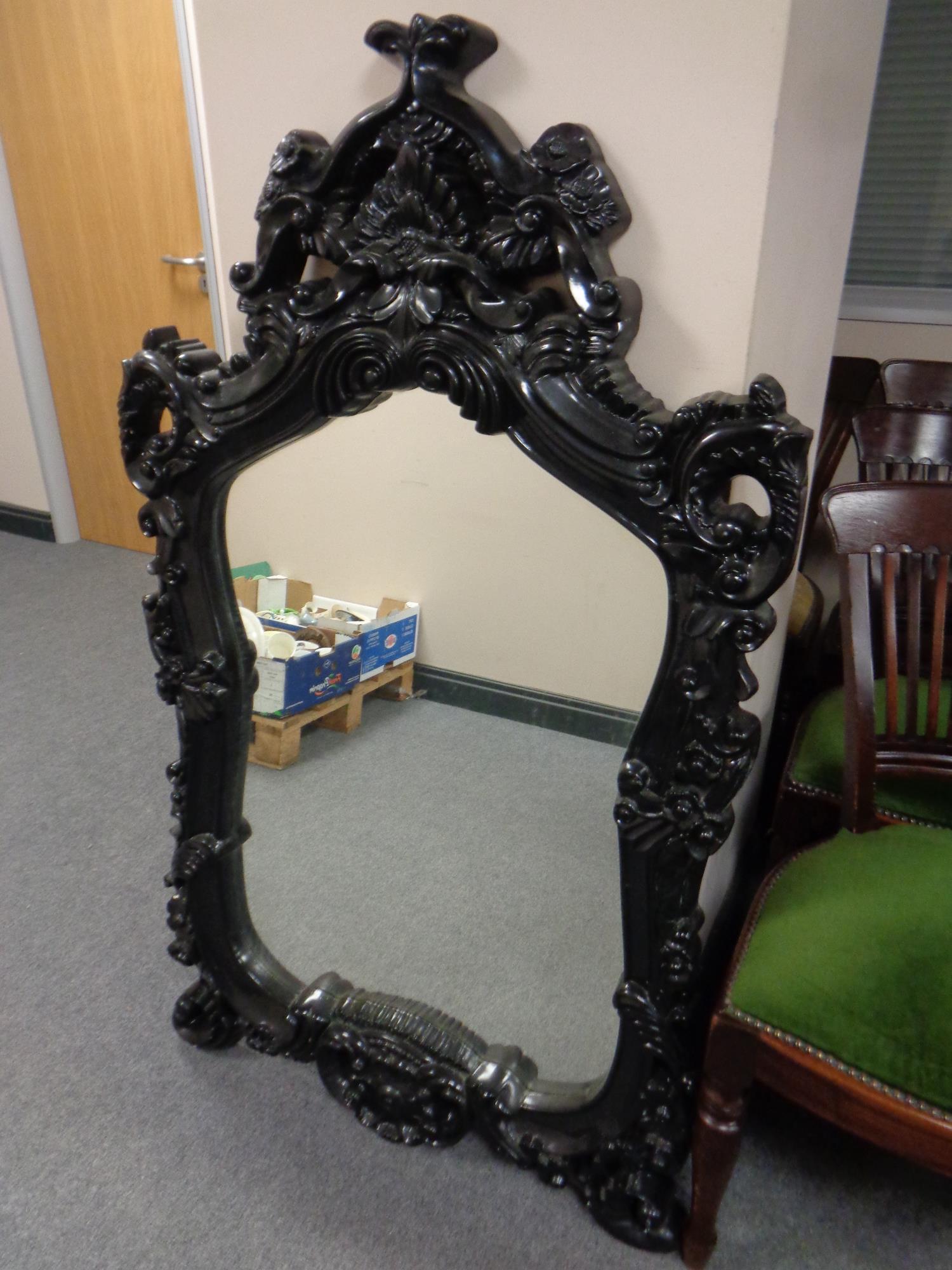 A contemporary black framed rococo style mirror