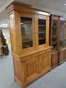 A Boissigny pine double door bookcase fitted cupboards and drawers beneath