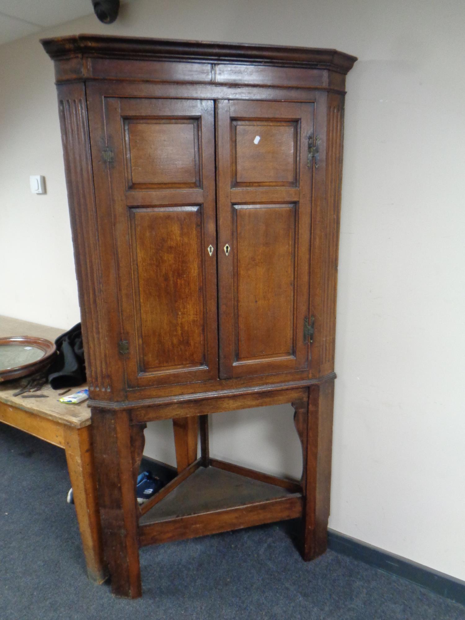 A George III oak double door corner cabinet on stand