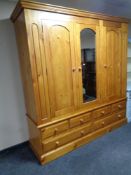 A contemporary pine triple door wardrobe with central mirrored door fitted six drawers beneath