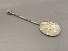 A silver embossed spoon depicting an African mother with child