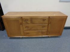 An Ercol solid elm and beech double door low sideboard fitted three central drawers