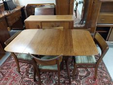 A 20th century teak extending dining table together with a set of four chairs and matching