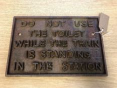 A metal railway plaque - "DO NOT USE THE TOILET WHILE THE TRAIN IS STANDING IN THE STATION",
