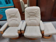 A pair of contemporary cream leather relaxer chairs together with a matching footstool