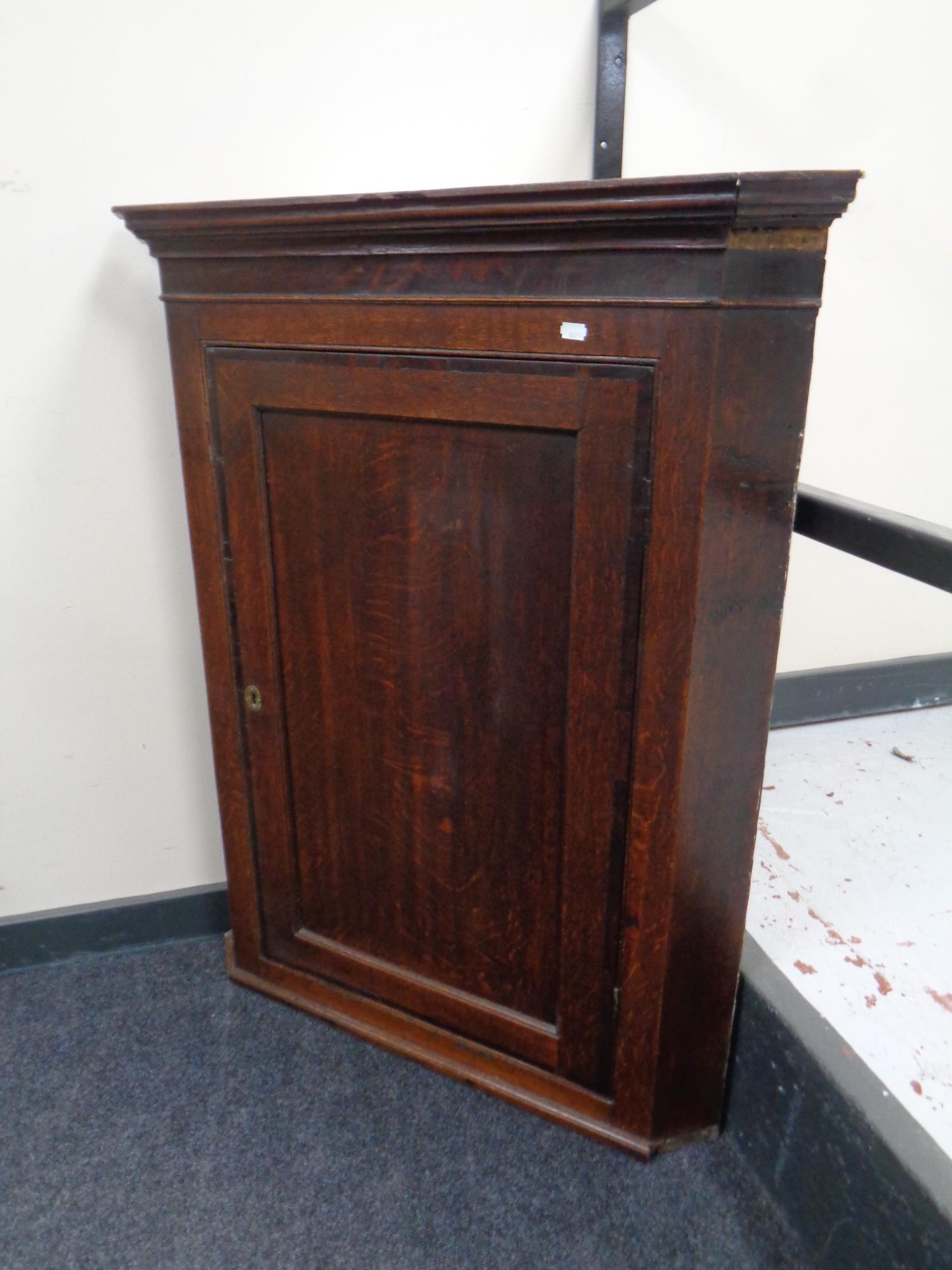 A George III oak panel door hanging corner cabinet