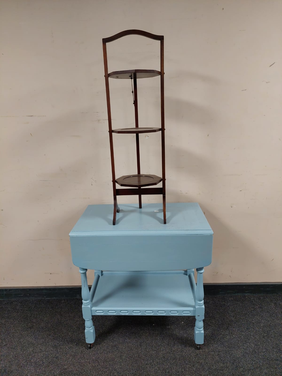 A painted drop leaf serving trolley on casters together with a three tier cake stand