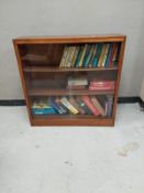 A walnut sliding glass door bookcase containing a quantity of 20th century volumes