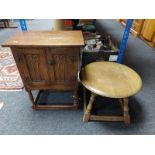 A carved oak double door low cabinet together with a circular oak occasional table