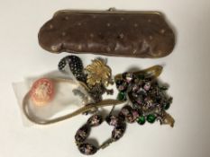 A vintage lady's purse containing a small quantity of costume jewellery,