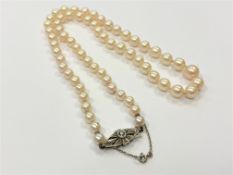 A single strand pearl necklace with 9ct white gold sapphire and diamond clasp, length 49cm.