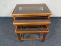 A nest of three teak and smoked glass tables,