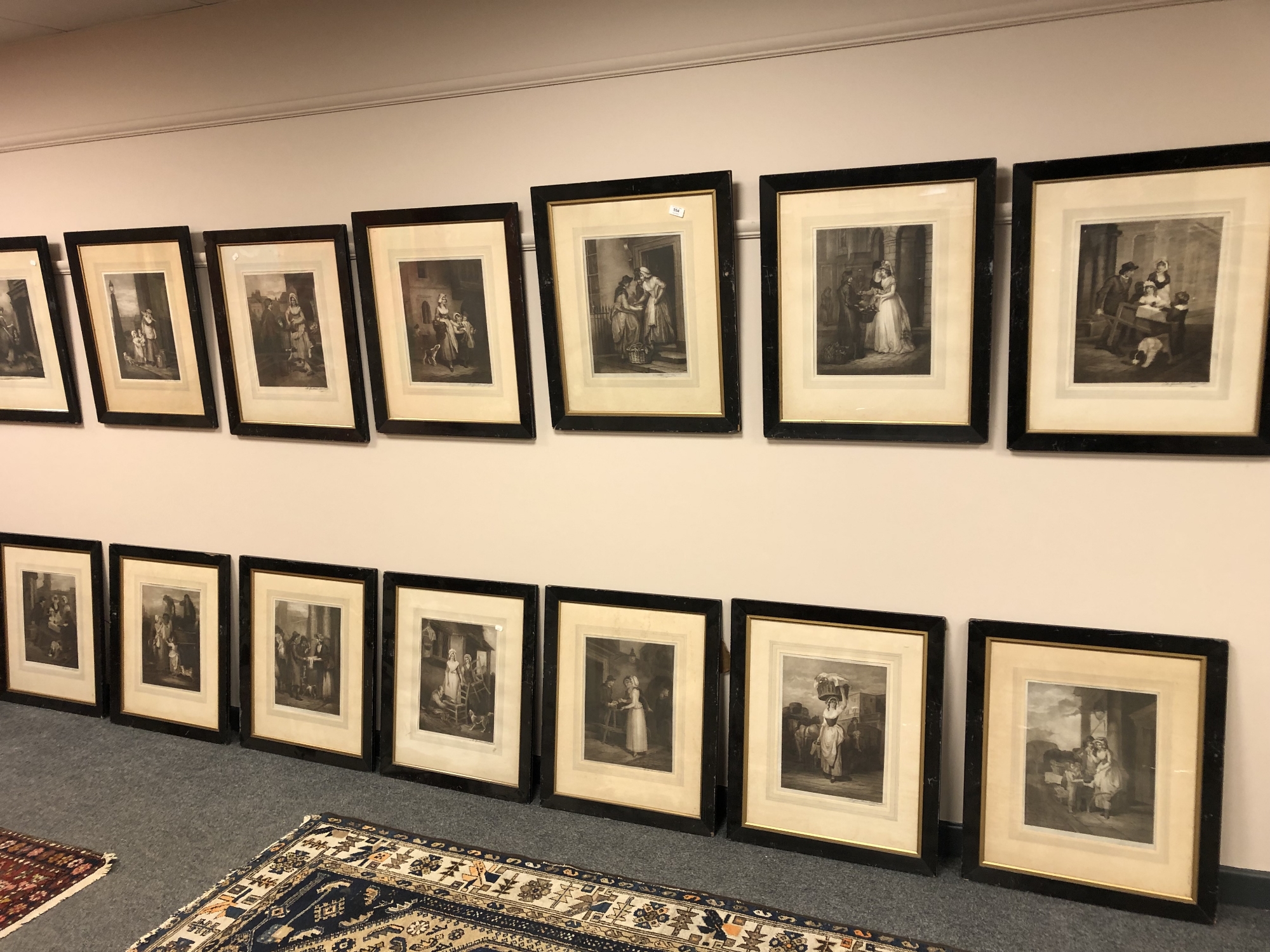 A set of 15 monochrome engravings depicting figures and taverns, in ebonised frames.