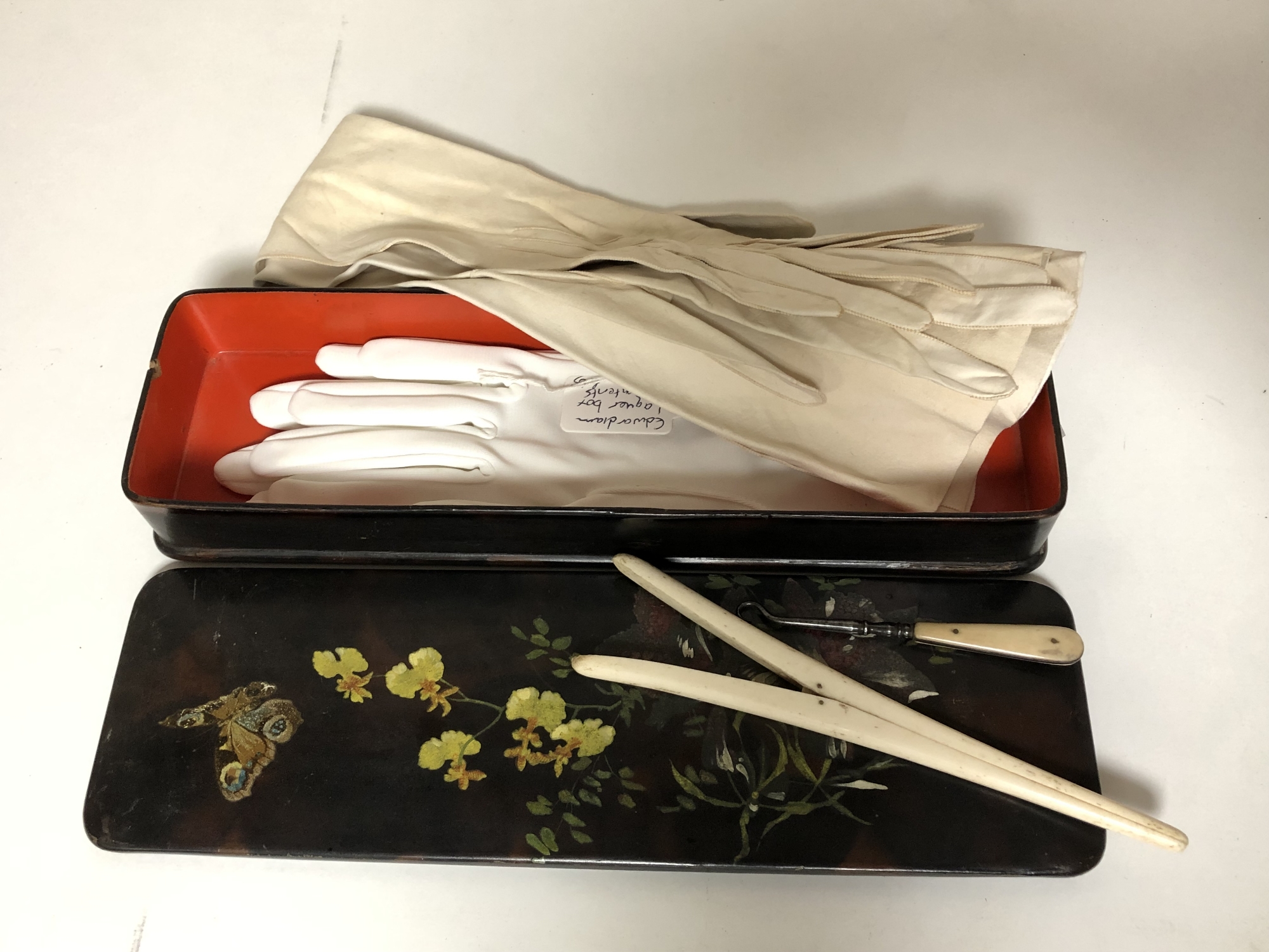 An Edwardian painted glove box containing a pair of lady's calf skin gloves, ivory glove stretchers,