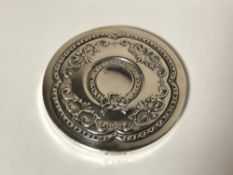 A small circular hand mirror with embossed silver back
