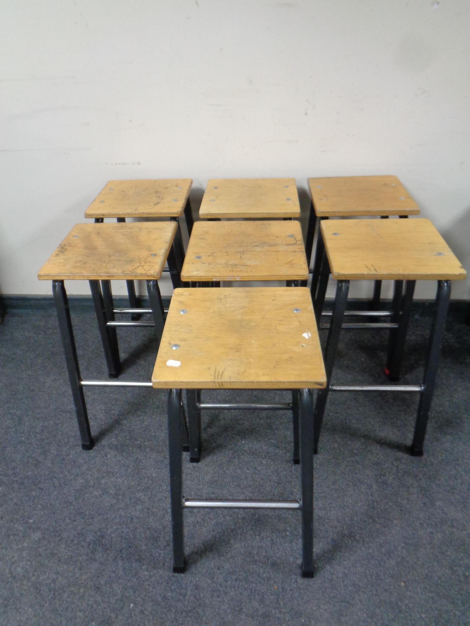 A set of seven plywood topped science lab stools on metal legs