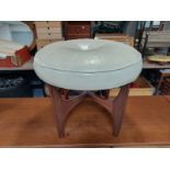 A 20th century teak circular footstool upholstered in cream leather