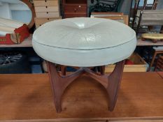 A 20th century teak circular footstool upholstered in cream leather