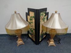 A pair of gilt composite table lamps with tasseled shades together with an oriental style two fold