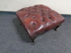 An oxblood leather Chesterfield buttoned footstool on cabriole legs,