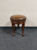An early 20th century carved beech circular stool on cabriole legs with studded leather seat