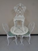 A cast metal circular garden table together with a pair of chairs and one further chair