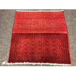 An eastern fringed cushion cover on red ground,