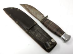 A vintage hunting knife in brown leather sheath,