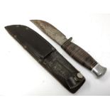 A vintage hunting knife in brown leather sheath,
