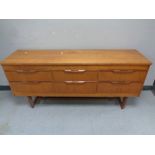 A 20th century teak six drawer chest on raised legs,