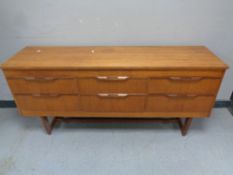 A 20th century teak six drawer chest on raised legs,