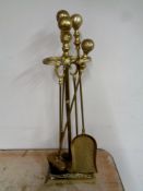 A four piece antique brass fire companion set on stand