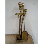 A four piece antique brass fire companion set on stand