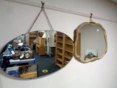 An early 20th century oval frameless mirror together with a further shaped mirror in composite