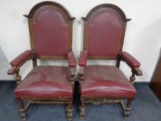 A pair of Edwardian oak high backed armchairs upholstered in a red leather