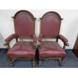 A pair of Edwardian oak high backed armchairs upholstered in a red leather